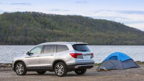 A used 2016 Honda Pilot SUV parks next to a lake.