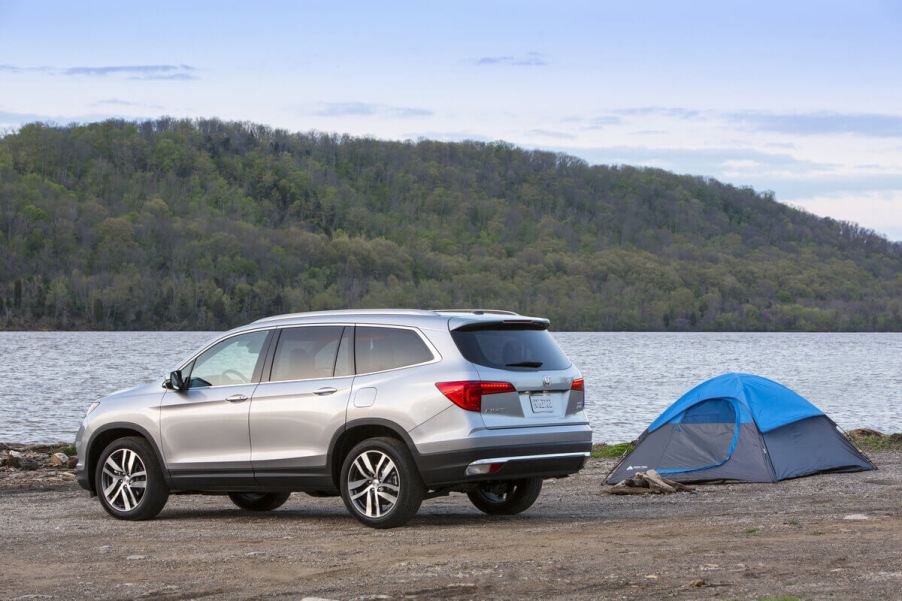 A used 2016 Honda Pilot SUV parks next to a lake.