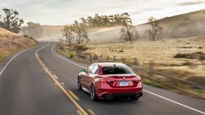 An red Alfa Romeo Giulia without a manual transmission cruises a highway with no other cars.