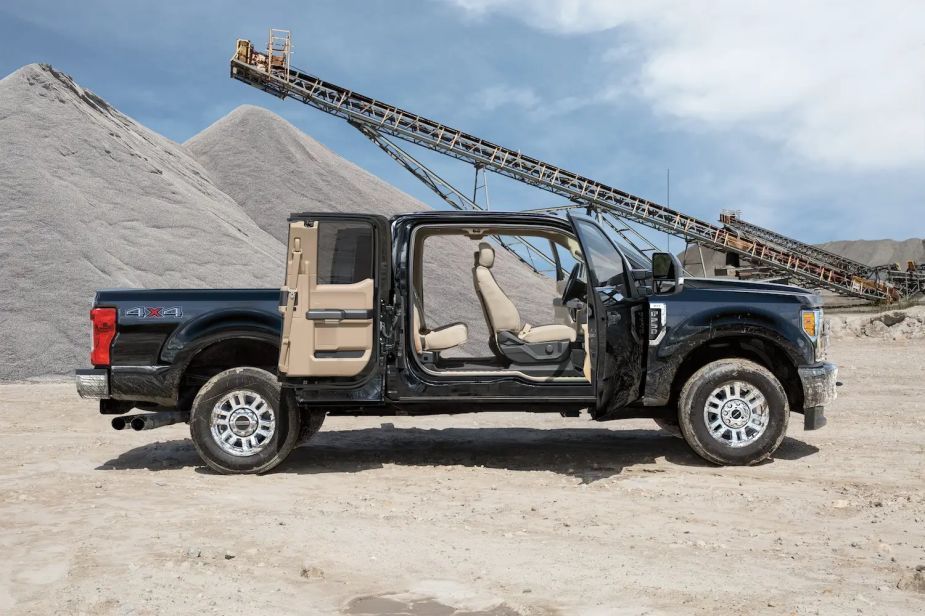 A Ford SuperDuty with a Super Cab configuration parked in a gravel pit with its rear-hinged rear doors open.