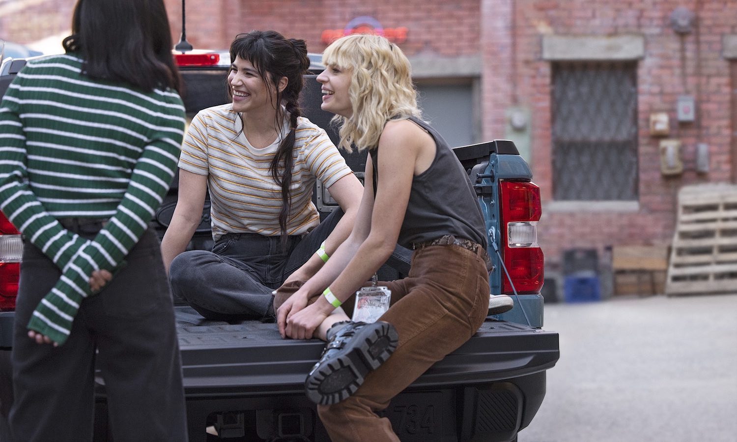 Three people sitting in the bed of a Ford Maverick.