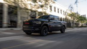 A black 2022 Ram 1500 (RAM)RED Edition full-size pickup truck driving through a city with a blurred background