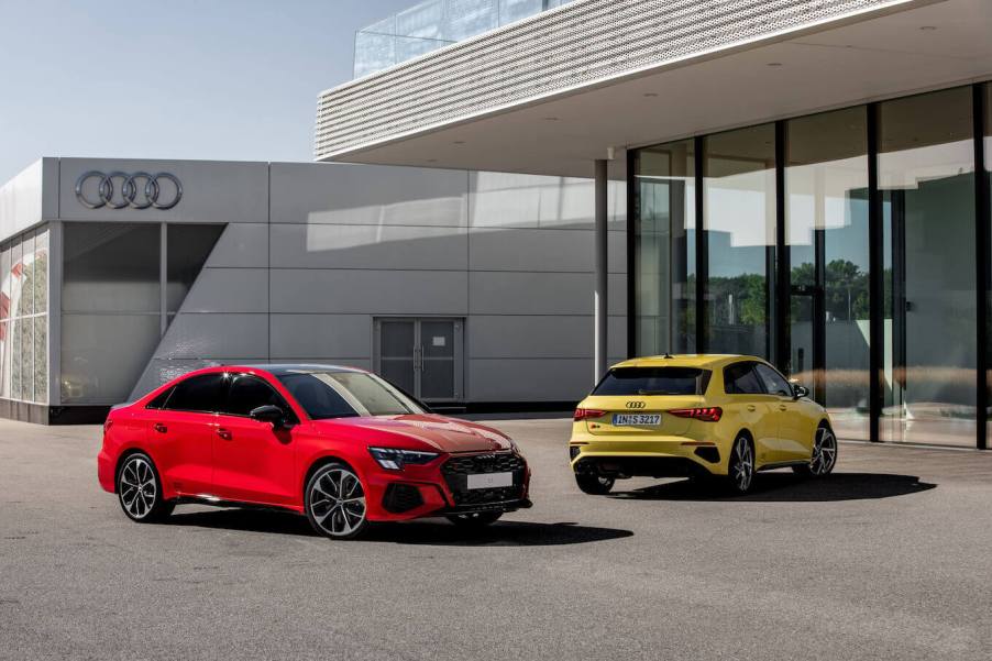 A red 2023 Audi S3 parked in front of another yellow Audi model in front of a building