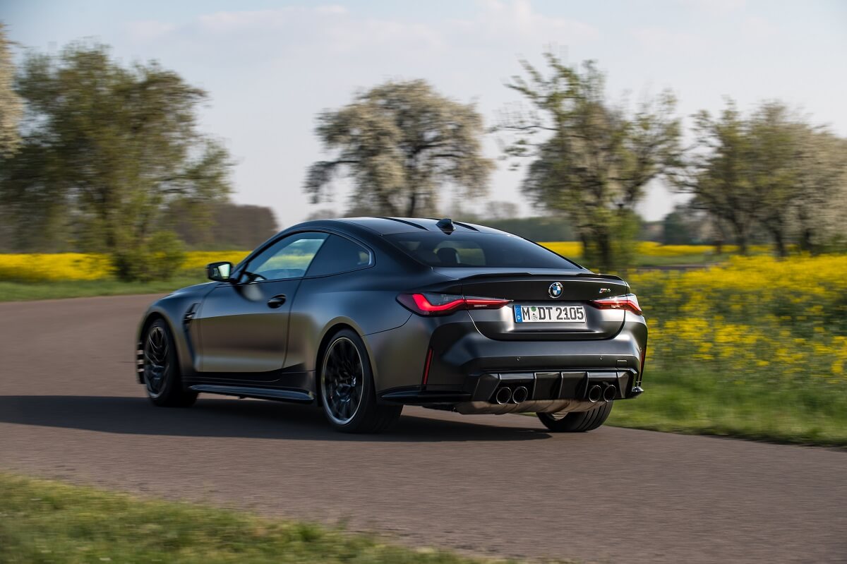 A matte black 2023 BMW M4 with a manual transmission drives country roads.