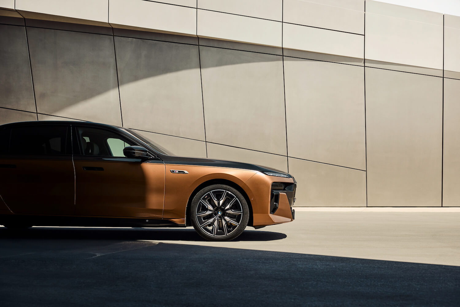 The BMW i7 half covered in shadows, a wall visible in the background.