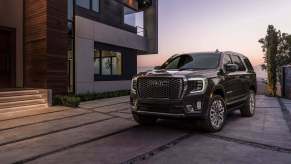 The 2023 GMC Yukon Denali Ultimate exterior in front of a modern building at dusk.