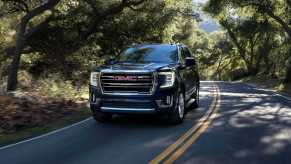 The 2023 GMC Yukon driving on a wooded road.