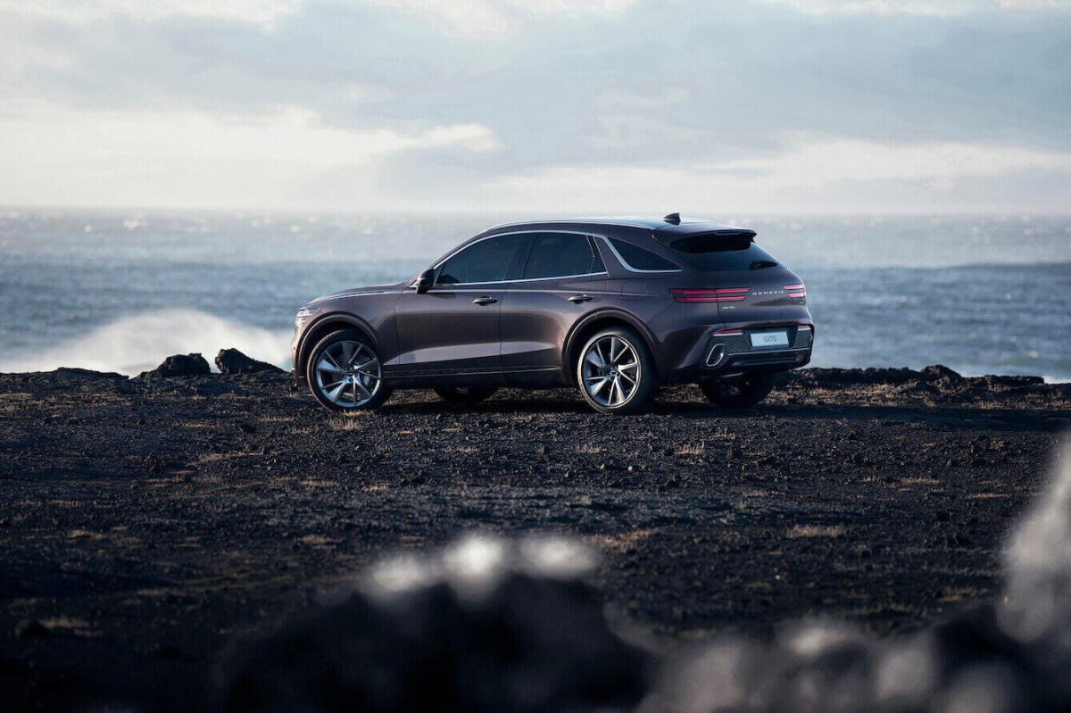 A gray 2023 Genesis GV70 driving parked on a rocky cliff