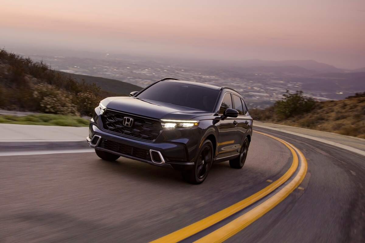 A black 2023 Honda CR-V Sport Touring SUV traveling uphill on a two-lane highway. The Honda CR-V is one of the best-selling Honda models of all time. 