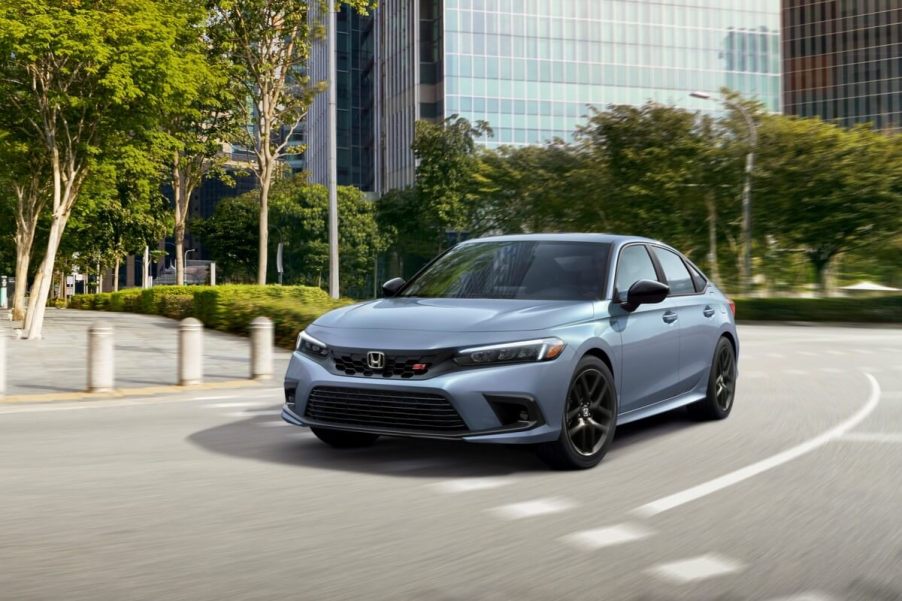 A gray-blue 2023 Honda Civic Si drives on urban streets.