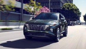 A black 2023 Hyundai Tucson Plug-In Hybrid small plug-in hybrid SUV is driving.