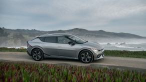 A gray 2023 Kia EV6 electric compact SUV model parked on a hill overlooking foggy sea water