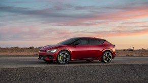 Red 2023 Kia EV6 at sunset driving on the road.