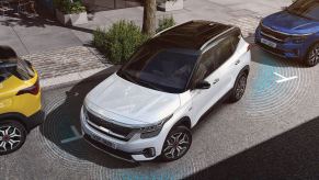 The 2023 Kia Seltos in white using parking sensors to parallel park.