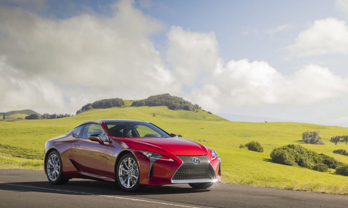 A red 2023 Lexus LC 500 parked near a green field