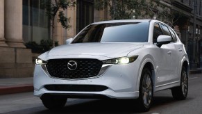 A white 2023 Mazda CX-5 small SUV is driving on the road.