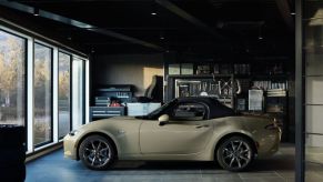 A tan 2023 Mazda MX-5 Miata in a garage.