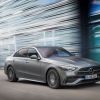 A gray 2023 Mercedes Benz C-Class driving next to a tall glass building