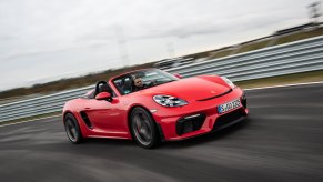 A red 2023 Porsche 718 Boxster driving on a track