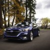 Blue 2023 Subaru Legacy driving down a suburban road.