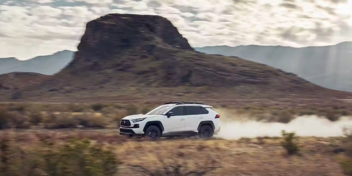 A white 2023 Toyota RAV4 driving off-road.