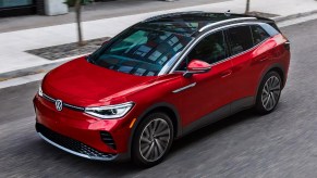 A red 2023 Volkswagen ID.4 small electric SUV is driving on the road.