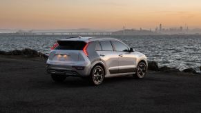 A silver 2023 Kia Niro EV parked on the shore at dusk.