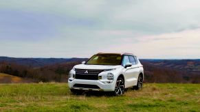 A white 2023 Mitsubishi Outlander PHEV on display in an open field.