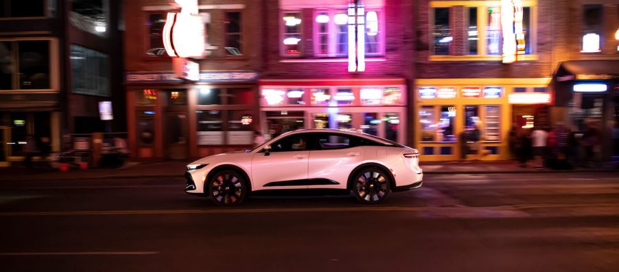 A white 2023 Toyota Crown on the street at night with neon lights in the background.