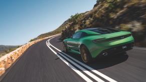 The back of a green Aston martin DB12 as it races along a mountain road.