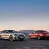 A white and red 2024 BMW 5 Series gas and electric sedan parked next to each other