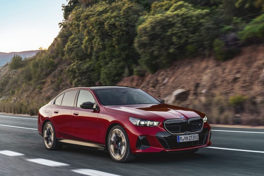 A red 2024 BMW I5 M60 driving down a two lane road