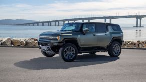 A 2024 GMC Hummer EV SUV model in Moonshot Green Matte parked near a bridge over water