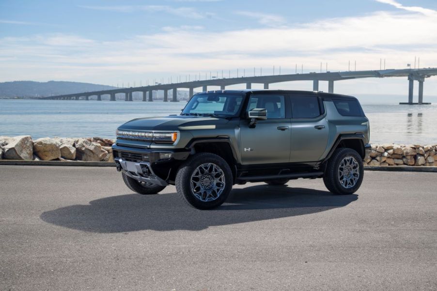 A 2024 GMC Hummer EV SUV model in Moonshot Green Matte parked near a bridge over water