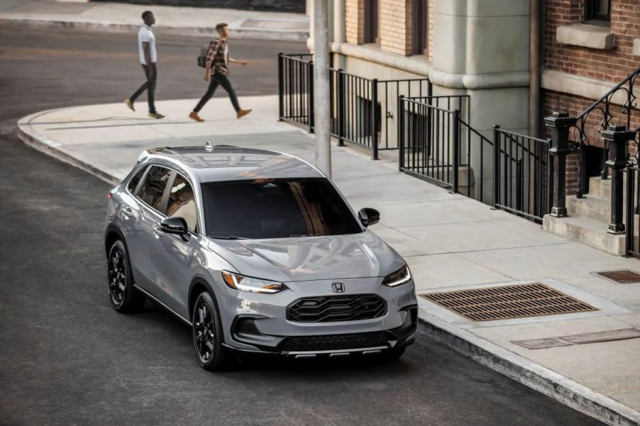 A gray 2024 Honda HR-V Sport subcompact SUV model parked on the side of a city street near a sewer grate