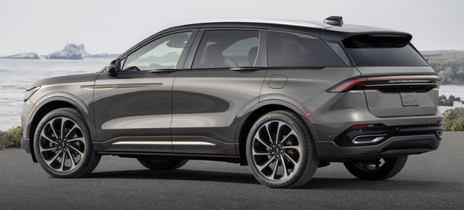 A side profile shot of a 2024 Lincoln Nautilus Hybrid Black Label midsize luxury SUV model parked by calm water