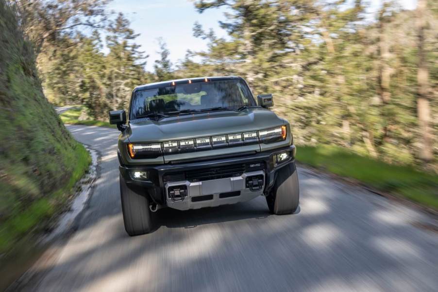 The 2024 GMC Hummer EV driving down a road in the forest.