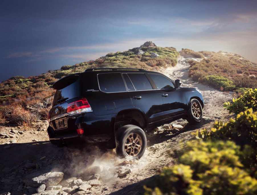 A black 2021 Toyota Land Cruiser climbs up an off-road trail. The Land Cruiser was discontinued in America after the 2021 model year.