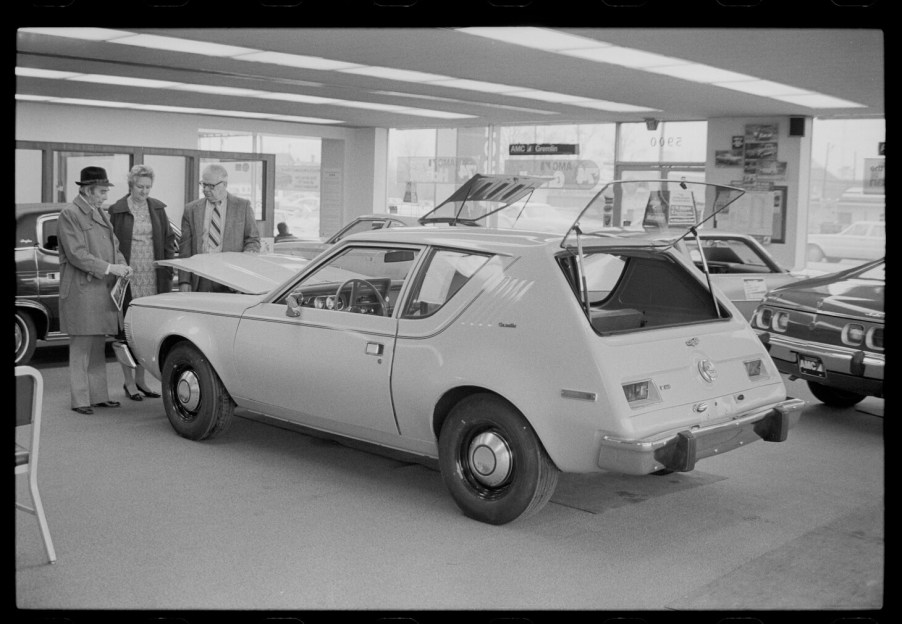 An unidentified couple (at left) speaks with an automobile salesman about an American Motors Corporation (AMC) Gremlin in showroom