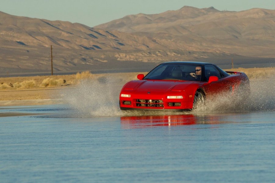 A first-generation Acura NSX driving through the water.