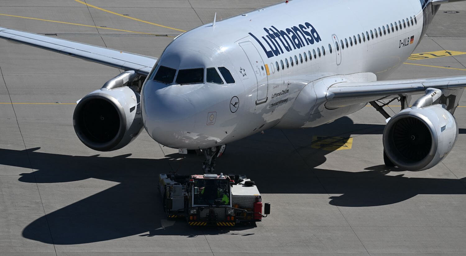 A pushback tug moves a jet airplane along a runway.