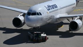 A pushback tug moves a jet airplane along a runway.