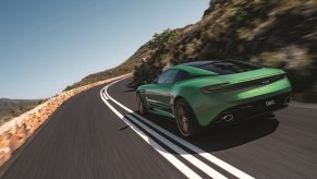 An Aston Martin DB12 flexes its grand tourer muscle by cornering on a mountain pass.