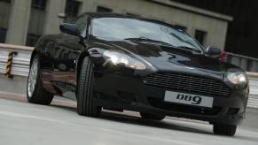 A black Aston Martin DB9 car in a parking lot.