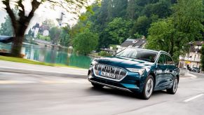 An Audi e-tron luxury electric car blasts across a city street.