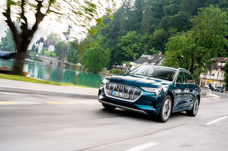 An Audi e-tron luxury electric car blasts across a city street.