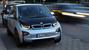 A BMW i3 plugged into a charging station, which is offered with an available engine range extender