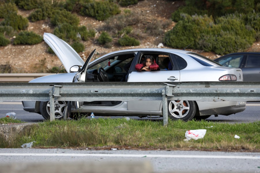 girl looking out the window of a broken down car