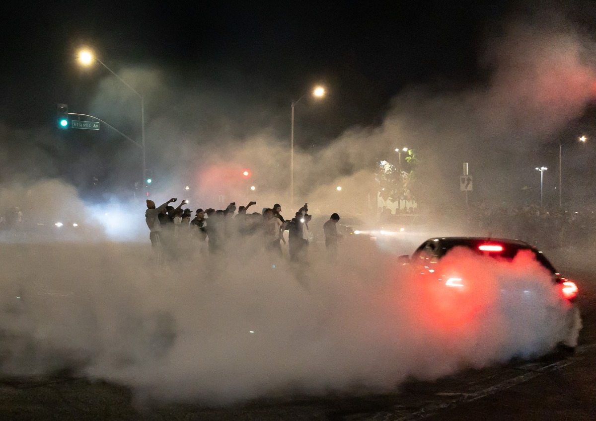 Car sideshow with car doing donuts on public road