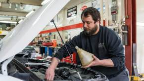 An auto mechanic completes an oil change on a customer's vehicle. Oil change is part of the maintenance schedule.